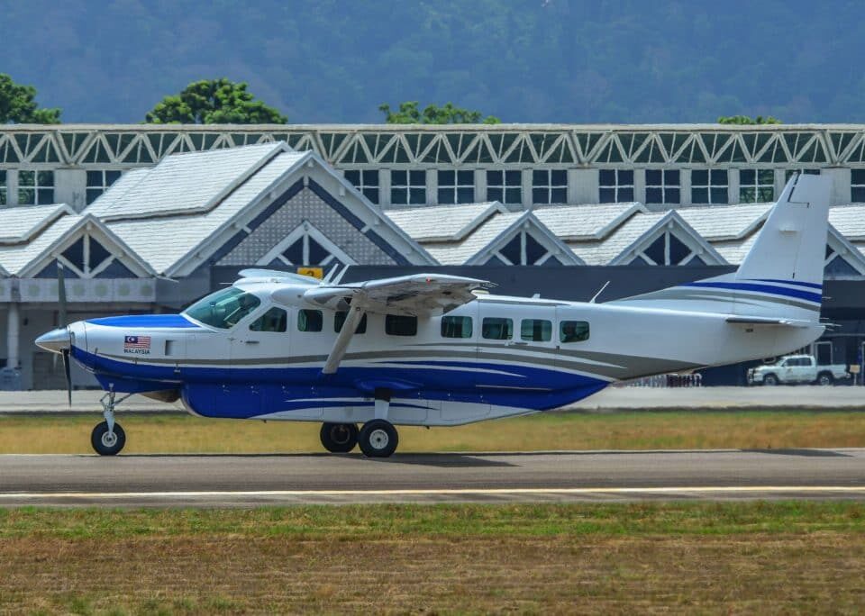 Cessna Caravan 208B EX taxiing on airfield with terminal in background