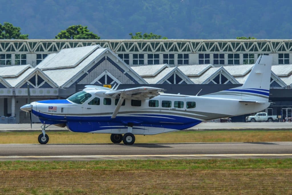Cessna Caravan 208B EX taxiing on airfield with terminal in background