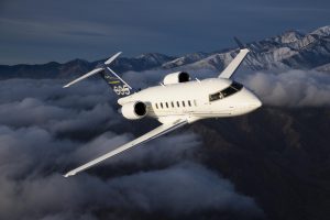 Challenger 605 business jet flying over mountainous terrain