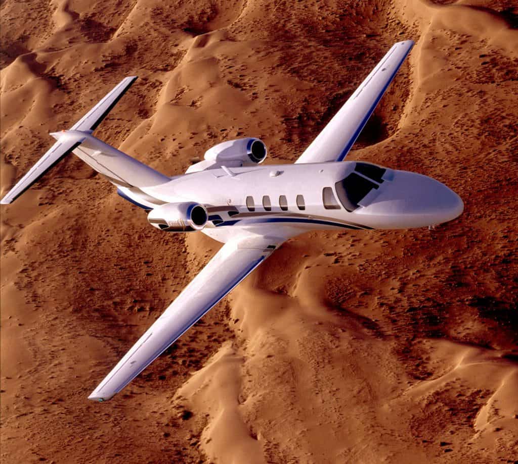 Cessna Citation CJ1 jet flying above sand dunes in the desert.