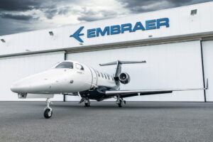 Embraer Phenom 300E on ramp in front of hangar with dramatic sky