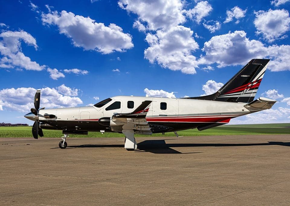 Socata TBM 960 parked on ramp under blue sky with scattered clouds