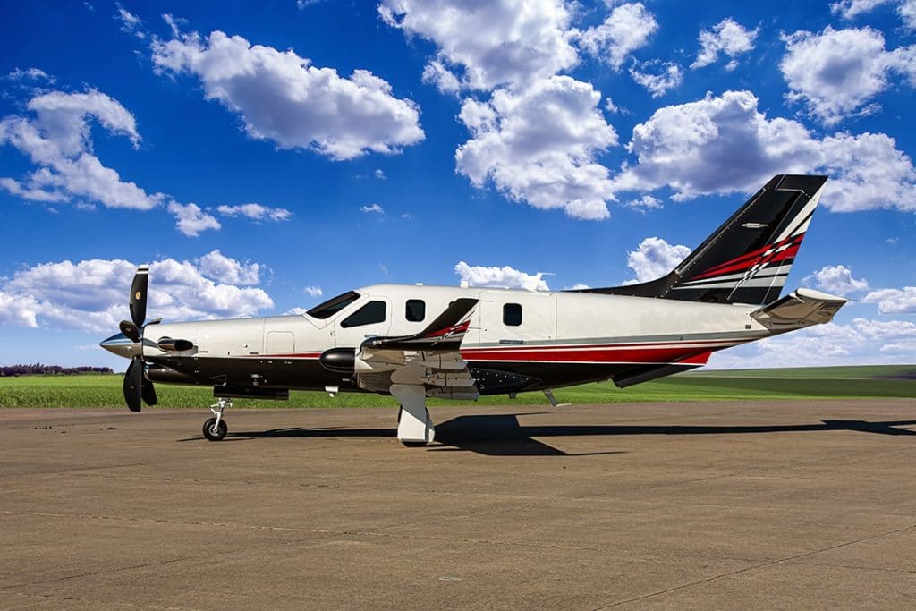 Socata TBM 960 parked on ramp under blue sky with scattered clouds