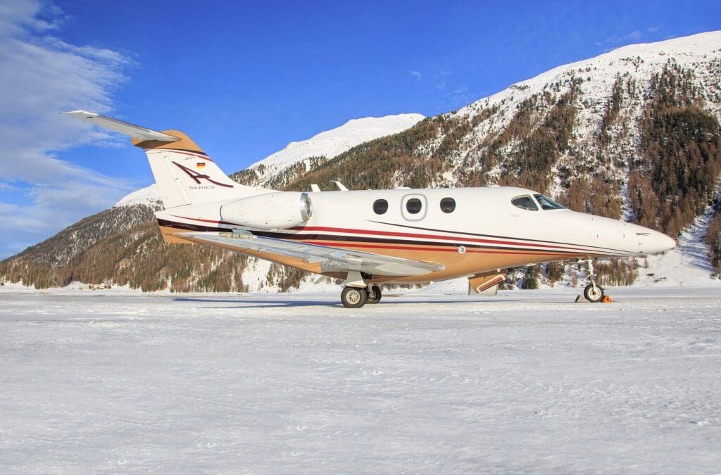 Beechcraft Premier 1A parked on snowy runway with mountain backdrop