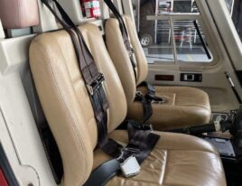 1999 Bell 407 helicopter cockpit with dual tan leather seats and fire extinguisher