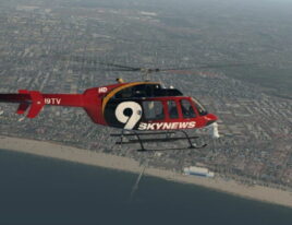 1999 Bell 407 helicopter in flight over coastal city and beachfront