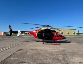 SkyNews-branded 1999 Bell 407 helicopter parked on sunlit concrete ramp