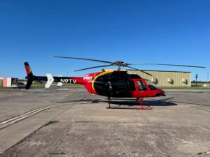 SkyNews-branded 1999 Bell 407 helicopter parked on sunlit concrete ramp