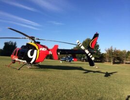 1999 Bell 407 SkyNews helicopter parked on grassy field with tail rotor visible