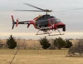 1999 Bell 407 helicopter hovering above rural field in overcast weather