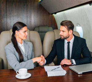 Business professionals shaking hands inside a private jet cabin.