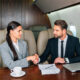 Business professionals shaking hands inside a private jet cabin.