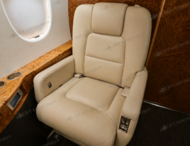2002 Dassault Falcon 2000 cabin interior featuring a cream leather executive seat and wood veneer finishes.