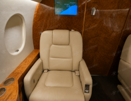 2002 Dassault Falcon 2000 cabin with cream leather executive seating, wood veneer finishes, and entertainment display.